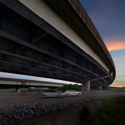 Car speeding past another car on empty highway.